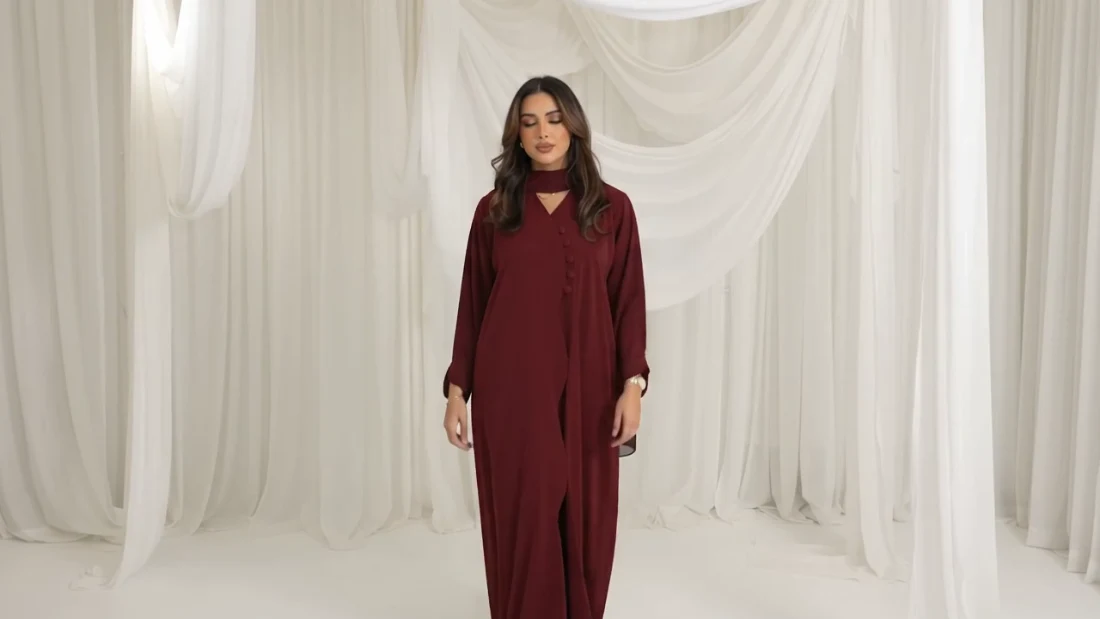 A burgundy SEEN abaya against ivory studio draping.